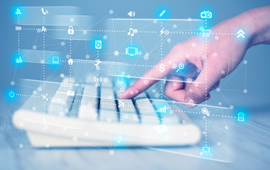 Hand pressing keyboard with high tech media icons