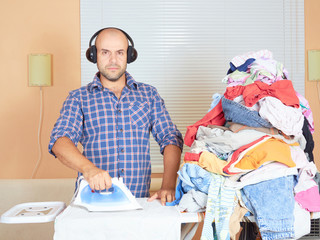 Caucasian man ironed clothes in the room near the window and lis © volkovslava