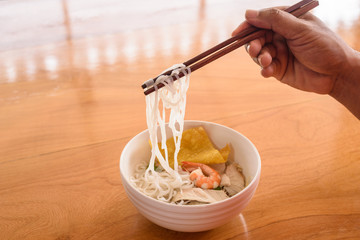 someone use shopsticks to eat noodles