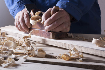 Carpenter working with plane on wooden background at Building Site. Joiner workplace