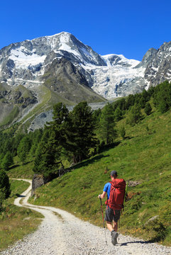 Alpinist on a gravel road on his way to the beautiful mountains of Arolla, Switzerland.