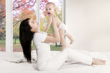 Obraz na płótnie Canvas Cheerful mother plays with baby