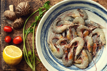 Raw fresh shrimps with ingredients on wooden background
