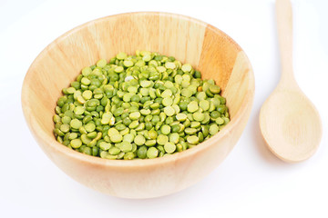 Close up of dried peeled split green bean in a wooden bowl on white background.