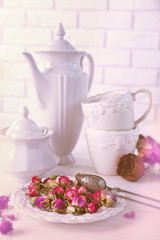 Obraz na płótnie Canvas Tea set and tea rose flowers on table on brick wall background