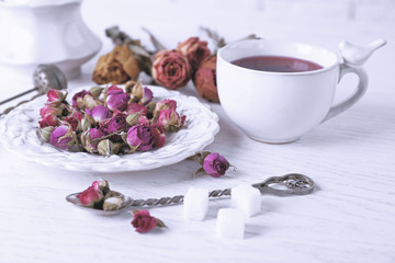 Tea and tea rose flowers on table closeup