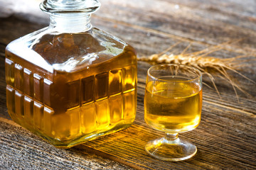 Glasse of brandy or cognac and bottle on  wooden table.