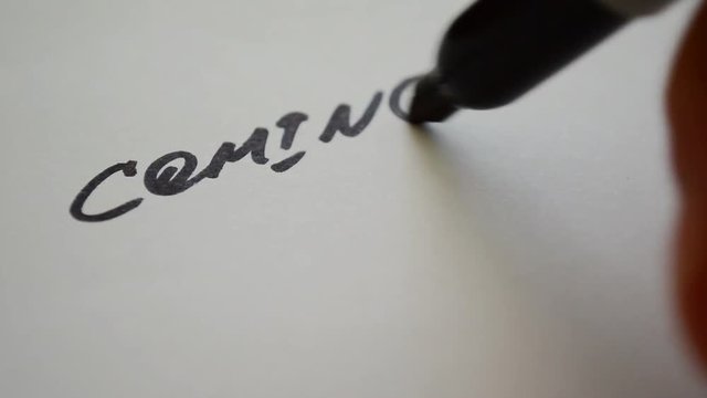 Coming soon, inscription on the paper writing with a marker