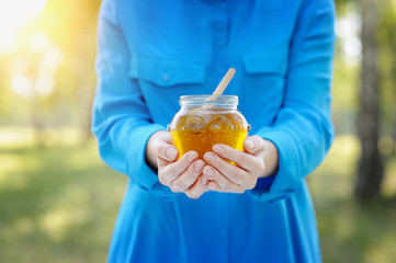 Closeup of a jar of honey in the hands of women.