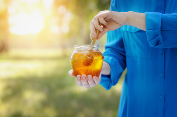 Closeup of a jar of honey in the hands of women.