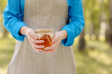 Closeup of a jar of honey in the hands of women.