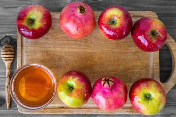 Honey, pomegranate and red apples on wood deck for Rosh Hashanah celebration. Jewish New Year Holiday.