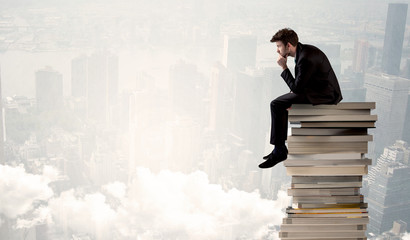 Student in city sitting on stack of books