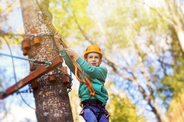 kid ready to zip line flight in adventure park. ziplining. brave child is ready to jump from a...