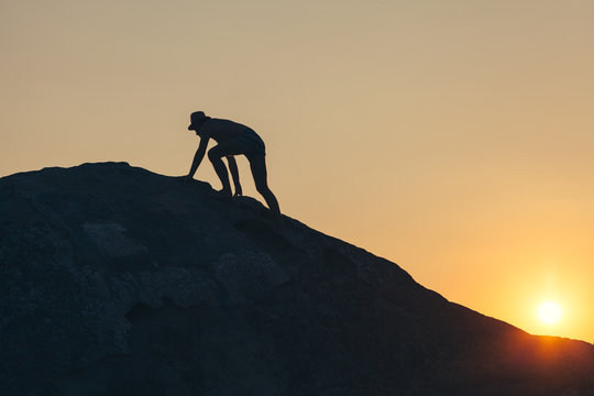 Man climbing up the hill to reach the peak in sunset