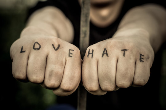 Man stretching his arms forward. Hands clenched into fists. In the hands of inscribed words "love" and "hate"
