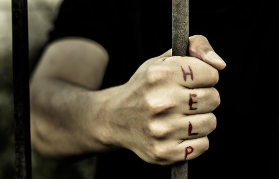 A man holds the hand of a metal rod. On the fingers is written "help."

