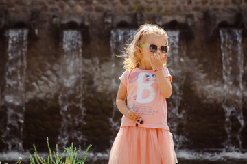 Summer portrait of a charming little 3-letnei girl in a pink dress and sunglasses. 