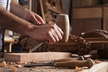 Hands of craftsman carve  with a gouge in the hands on the workbench in carpentry