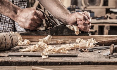 carpenter working with plane on wooden background