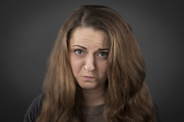 Naklejka premium Upset serious girl on a gray background 
