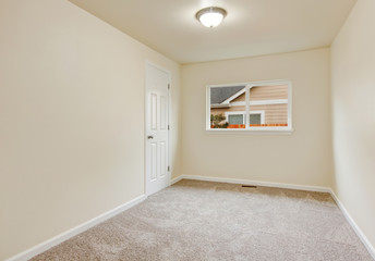 Small empty room in warm creamy tones with carpet floor