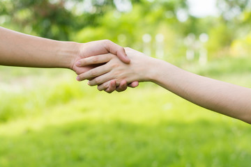 Close up on a man and a woman holding hands at green background,Hand help and hope concept,helping hand