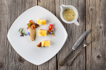 exclusive puff pastry appetizer with meat pie decorated with mushrooms and herbs on white plate with cutlery and sauce, product photography for restaurant