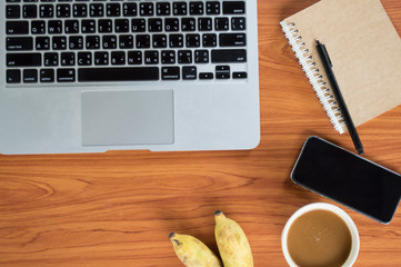 Office table with notepad, laptop and coffee cup.View from above with copy space.


