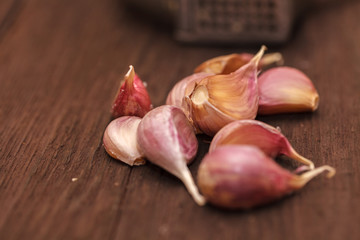 masher for garlic and garlic on a wooden background