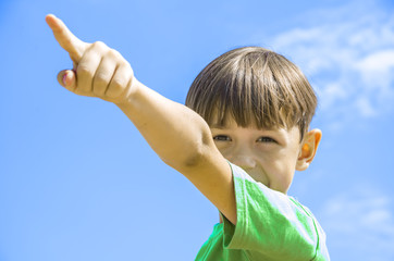 Мальчик на фоне синего неба указывает рукой  вверх  