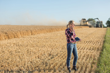 Naklejka na ściany i meble Female farmer using digital tablet in the wheat field