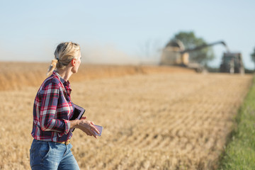 Naklejka na ściany i meble Female farmer using digital tablet in the wheat field