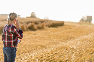 Naklejka na ściany i meble Modern female farmer with tablet on her wheat field