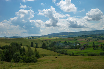 Summer day landscape with cloudy sky, mountains, small houses. Carpathian Mountains. Ukraine. Europe.