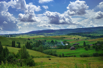 Obraz premium Summer day landscape with cloudy sky, mountains, small houses. Carpathian Mountains. Ukraine. Europe.