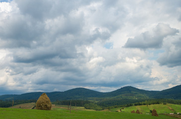 Summer day landscape with cloudy sky, mountains, small houses. Carpathian Mountains. Ukraine. Europe.