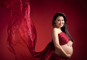 Pregnant woman on a red background in studio