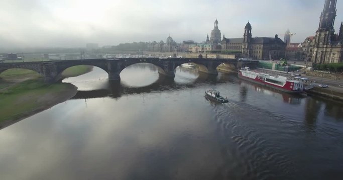 Aerial camera tracks a small boat along the Elbe River in front of the Dresden Skyline