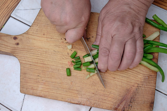 Cut with a knife raw green beans on a wooden board,