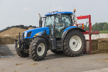 Blue tractor with a red bale slicer.