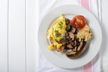 English breakfast with egg, sausage, vegetable, mushrooms, bread and tomato.