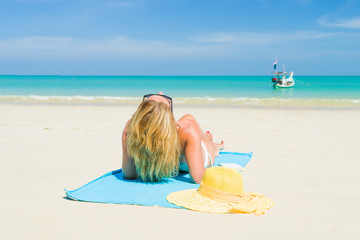 Woman lies on the beach with yellow hat and towel