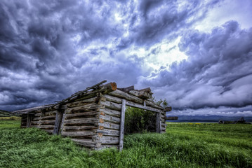 Some old abandon log buildings just outside of Yampa, Colorado with building storm clouds in the sky.