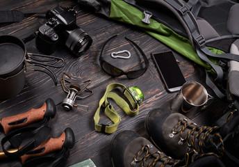 Hiking accessories set on dark wooden background:  boots, backpa