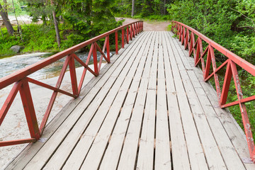 Bridge with red railings over stream in summer