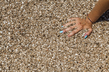 Female hand with cyan nails sinking in the sand