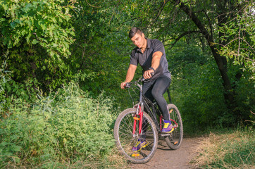 Obraz premium Mountainbiker riding on bicycle in summer park at sunny day.