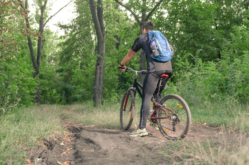 Mountainbiker riding on bicycle in summer park at sunny day.