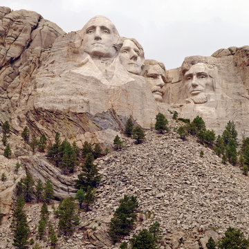 Sculpted images under a cloudy sky of Presidents George Washington, Thomas Jefferson, Theodore Roosevelt, and Abraham Lincoln at Mt. Rushmore National Memorial, Keystone, South Dakota, U.S.A.